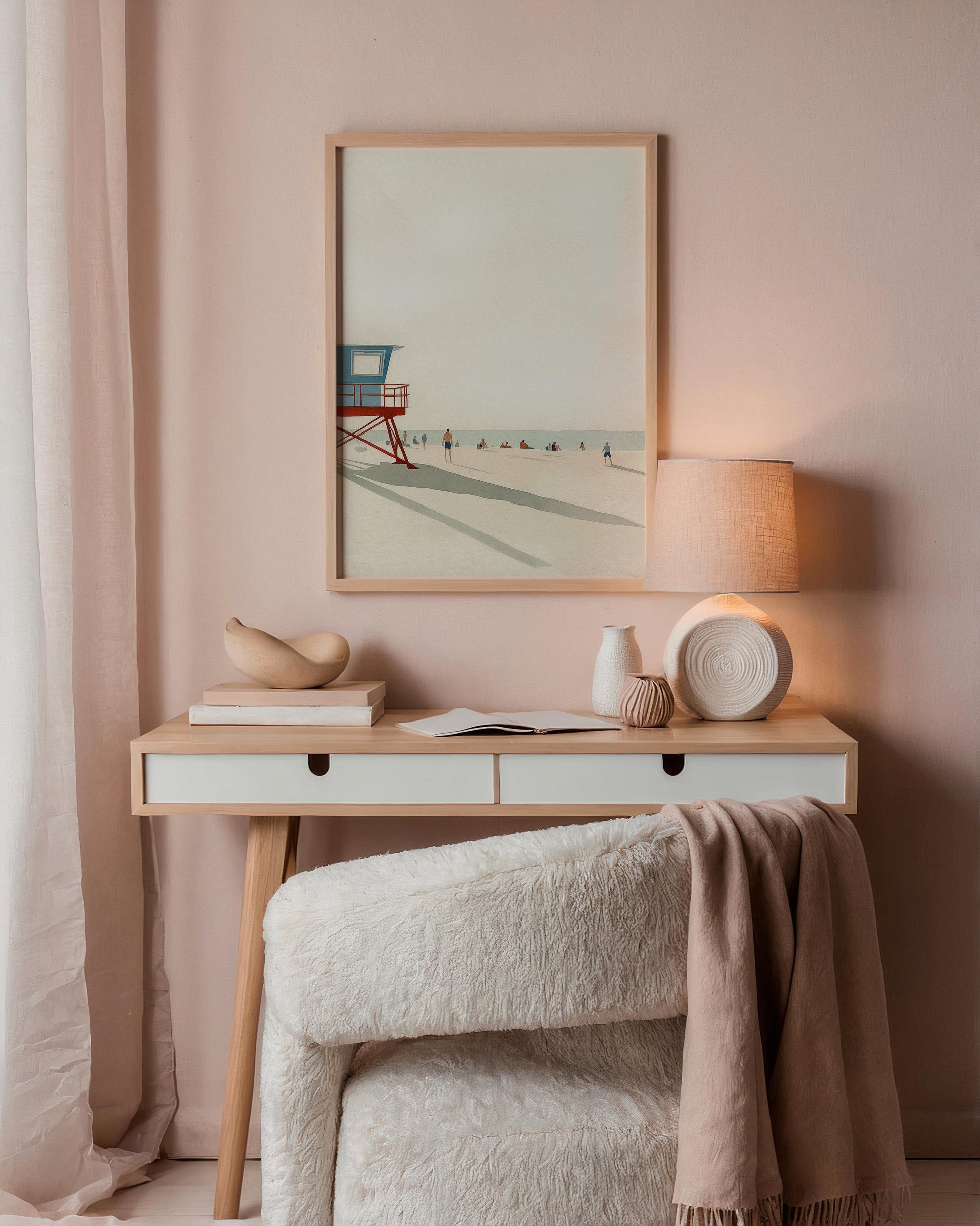 Nestled corner with a wooden desk against a pink wall, featuring a framed beach scene, lamp, and decorative items.